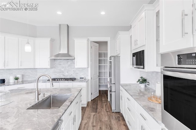 19887 Kershaw Ct, Monument, CO 80132 - kitchen with a sink, stainless steel appliances, wall chimney exhaust hood, white cabinetry, and recessed lighting
