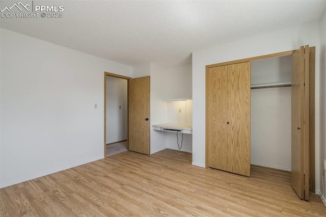 1559 Sausalito Dr, Colorado Springs, CO 80907 - unfurnished bedroom with light wood-type flooring, a closet, baseboards, and a textured ceiling