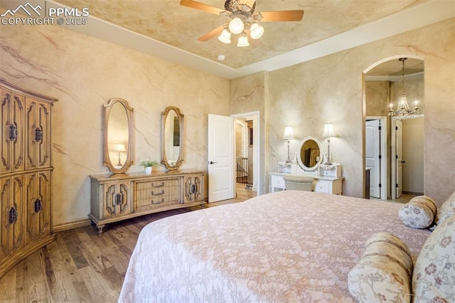 8396 Snow Cap Vw, Colorado Springs, CO 80920 - bedroom with wood finished floors, a chandelier, a ceiling fan, and arched walkways