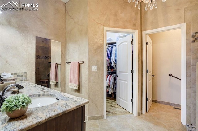 8396 Snow Cap Vw, Colorado Springs, CO 80920 - bathroom with a chandelier, a spacious closet, vanity, baseboards, and a textured wall