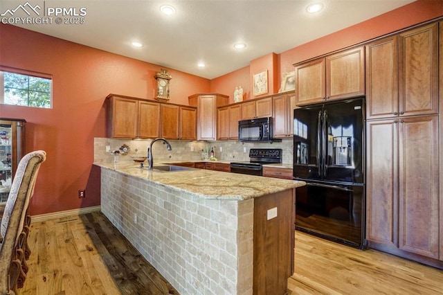 8396 Snow Cap Vw, Colorado Springs, CO 80920 - kitchen with black appliances, a sink, a peninsula, light stone countertops, and decorative backsplash