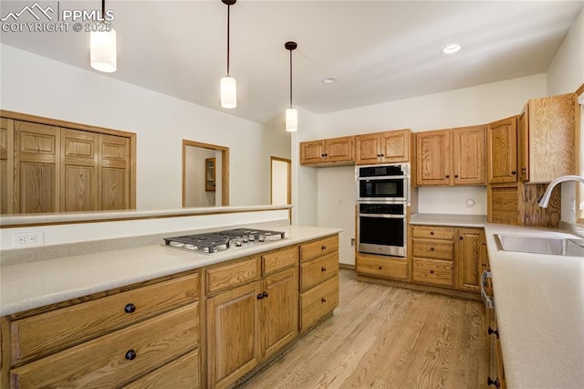 15635 Kingswood Dr, Colorado Springs, CO 80921 - kitchen featuring appliances with stainless steel finishes, light wood-type flooring, light countertops, brown cabinets, and pendant lighting