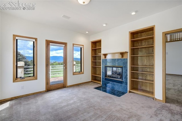 15635 Kingswood Dr, Colorado Springs, CO 80921 - unfurnished living room featuring carpet flooring, built in shelves, a tile fireplace, and recessed lighting