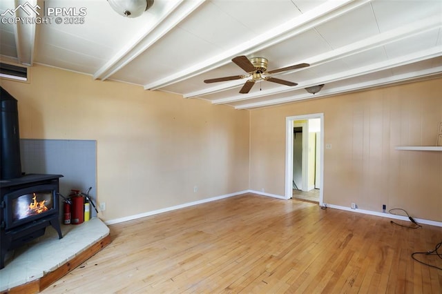 206 N 4th St, Victor, CO 80860 - unfurnished living room with beam ceiling, a wood stove, hardwood / wood-style floors, a ceiling fan, and baseboards