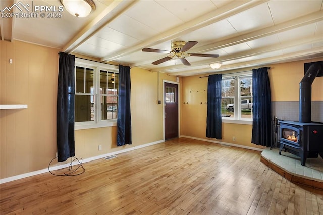 206 N 4th St, Victor, CO 80860 - unfurnished living room featuring wood-type flooring, a wood stove, beamed ceiling, ceiling fan, and baseboards