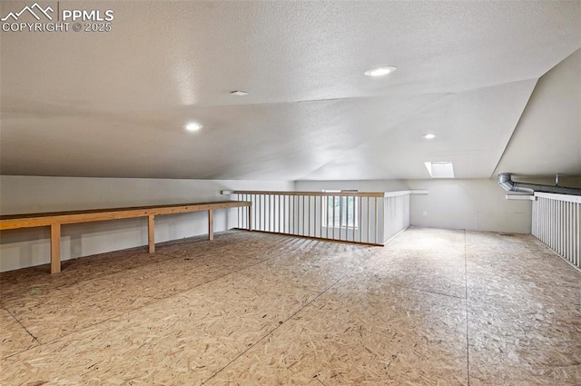 additional living space with vaulted ceiling, a skylight, and a textured ceiling