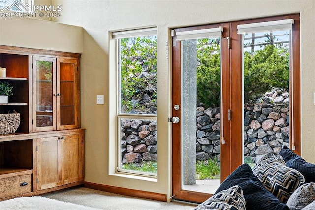 doorway featuring light carpet and baseboards