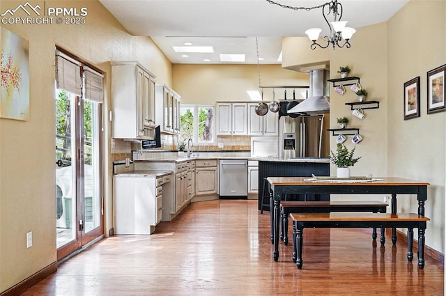 kitchen with stainless steel appliances, plenty of natural light, ventilation hood, and light countertops