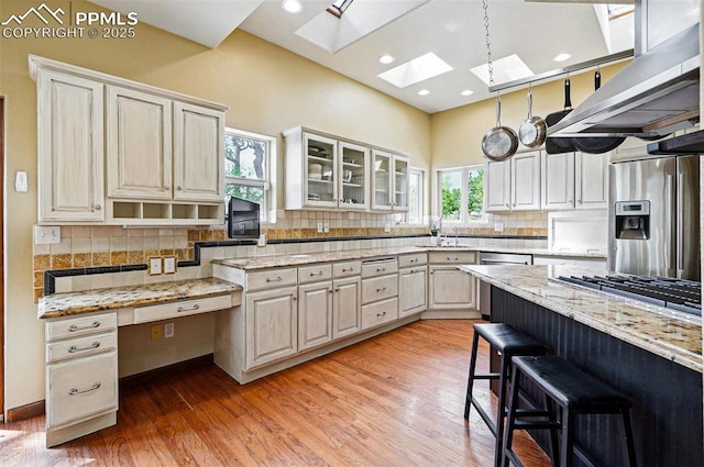 kitchen with stainless steel appliances, a skylight, decorative backsplash, light wood-style floors, and recessed lighting