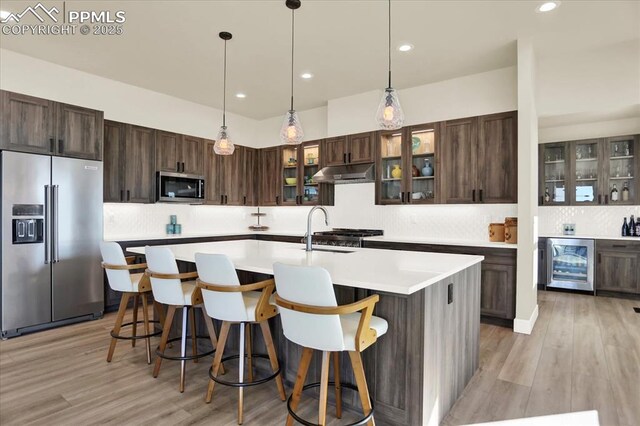 7871 Bannockburn Trl, Colorado Springs, CO 80908 - kitchen with appliances with stainless steel finishes, wine cooler, under cabinet range hood, decorative backsplash, and light countertops