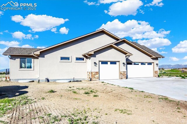 7871 Bannockburn Trl, Colorado Springs, CO 80908 - view of side of property featuring concrete driveway, stucco siding, an attached garage, a mountain view, and stone siding