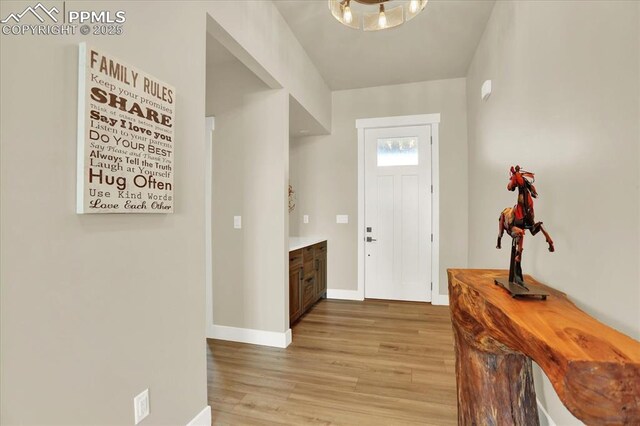7871 Bannockburn Trl, Colorado Springs, CO 80908 - foyer featuring baseboards, light wood-style floors, and a chandelier