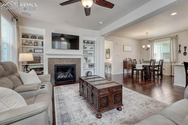 3793 Cadence Dr, Castle Rock, CO 80109 - living area with a ceiling fan, a chandelier, dark wood-style floors, a glass covered fireplace, and built in features