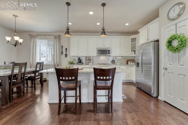 3793 Cadence Dr, Castle Rock, CO 80109 - kitchen with appliances with stainless steel finishes, dark wood-style flooring, white cabinetry, tasteful backsplash, and glass insert cabinets