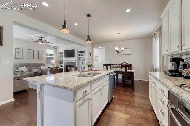 3793 Cadence Dr, Castle Rock, CO 80109 - kitchen with appliances with stainless steel finishes, a fireplace, white cabinetry, recessed lighting, and a chandelier