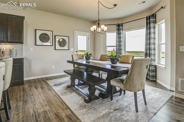 dining space with a chandelier, baseboards, and dark wood-type flooring