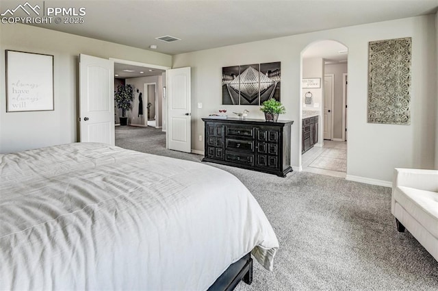bedroom featuring carpet, arched walkways, baseboards, and ensuite bathroom