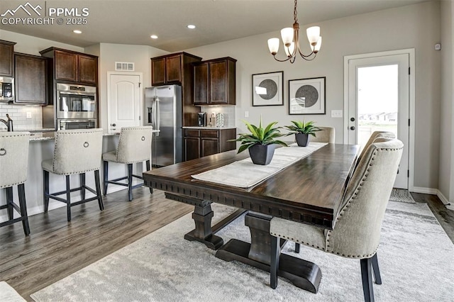 dining space with a chandelier, wood finished floors, and recessed lighting