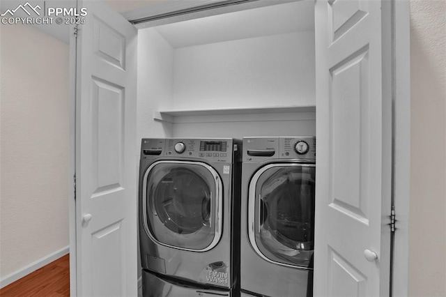 laundry area with washer and clothes dryer, wood finished floors, and baseboards