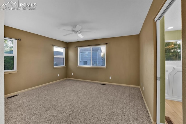 carpeted spare room with a ceiling fan and baseboards