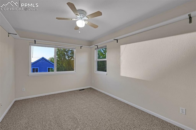 carpeted spare room with ceiling fan and baseboards