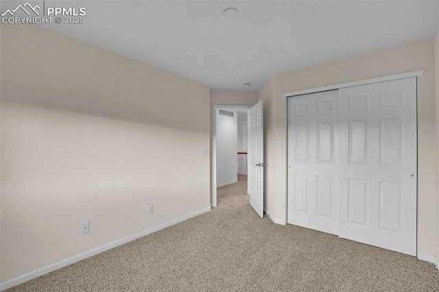 unfurnished bedroom featuring carpet flooring, baseboards, and a closet
