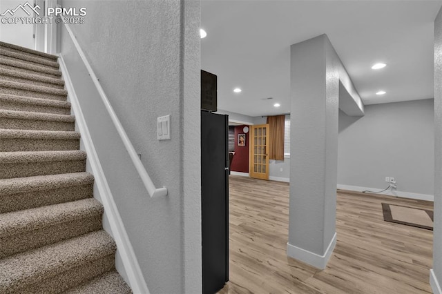 stairs with wood finished floors, baseboards, and recessed lighting