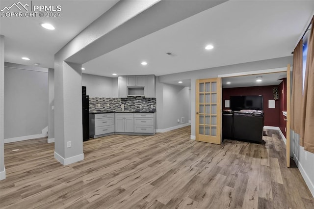 kitchen featuring open floor plan, light wood finished floors, baseboards, backsplash, and recessed lighting