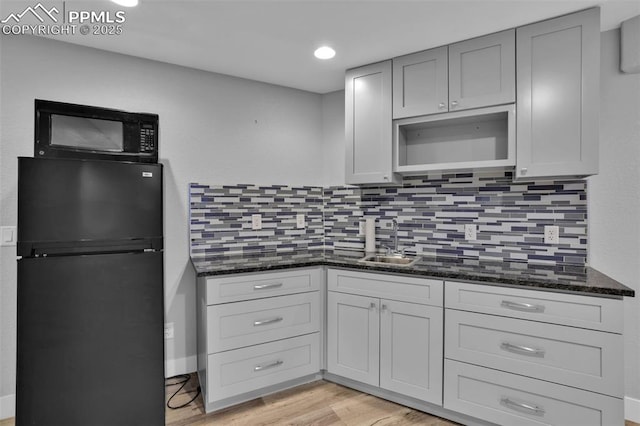 kitchen featuring black appliances, a sink, tasteful backsplash, dark stone counters, and recessed lighting