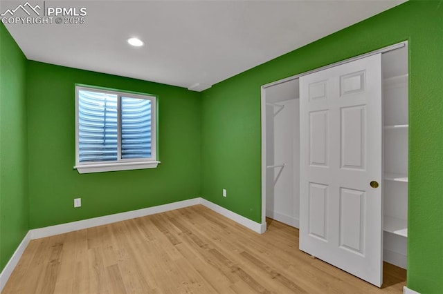 unfurnished bedroom featuring wood finished floors, a closet, baseboards, and recessed lighting