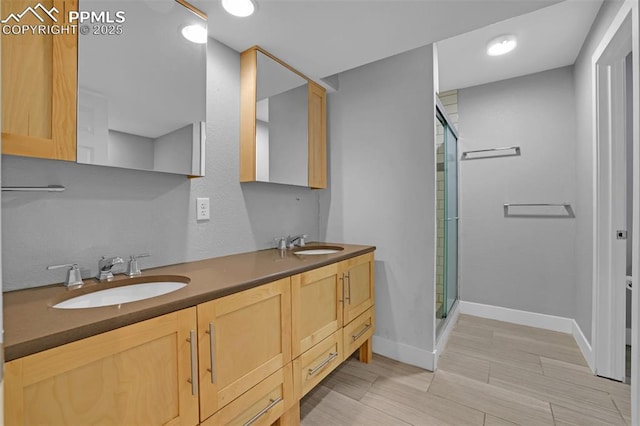 bathroom with a stall shower, baseboards, and double vanity