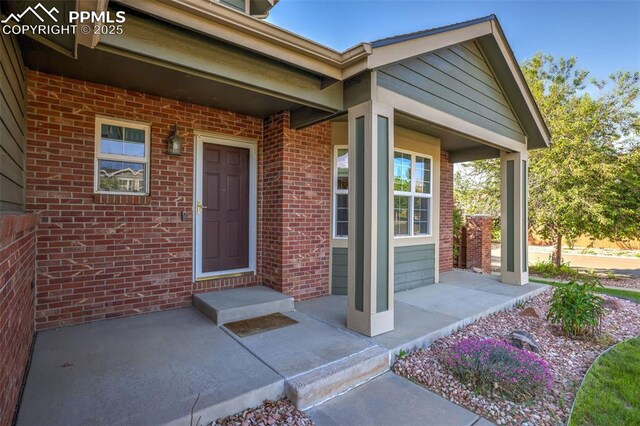 entrance to property featuring covered porch and brick siding