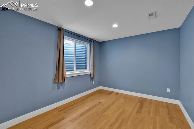 empty room with baseboards, wood finished floors, and recessed lighting