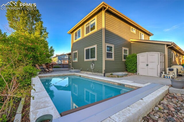 rear view of house featuring a patio, a storage unit, an outdoor pool, and an outbuilding