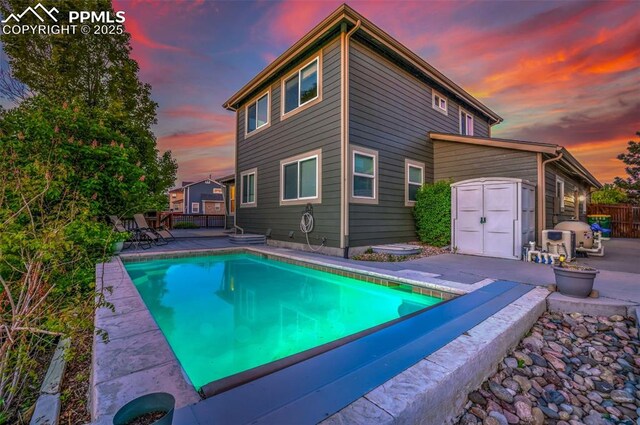 view of swimming pool featuring a shed, a patio, an outbuilding, and fence