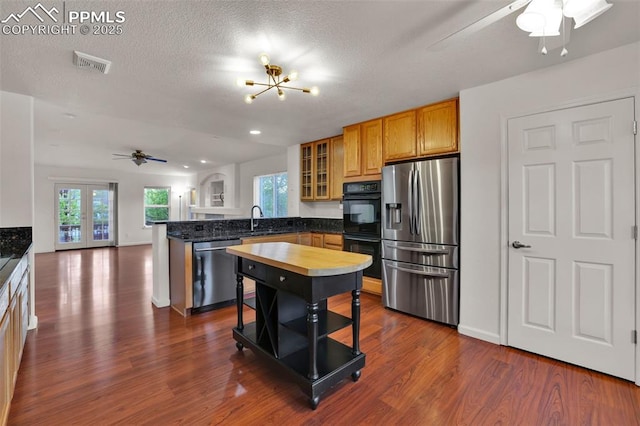 kitchen featuring stainless steel appliances, ceiling fan, a peninsula, a sink, and glass insert cabinets