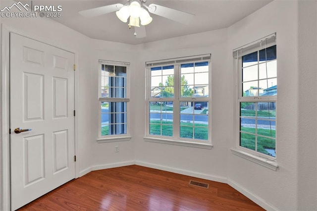 unfurnished room featuring wood finished floors, a ceiling fan, and baseboards