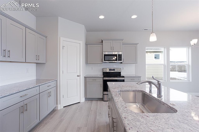 6045 Miller Run Pl, Colorado Springs, CO 80924 - kitchen with stainless steel appliances, a sink, gray cabinets, backsplash, and light wood finished floors
