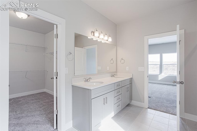 6045 Miller Run Pl, Colorado Springs, CO 80924 - full bathroom with double vanity, a walk in closet, baseboards, and tile patterned flooring