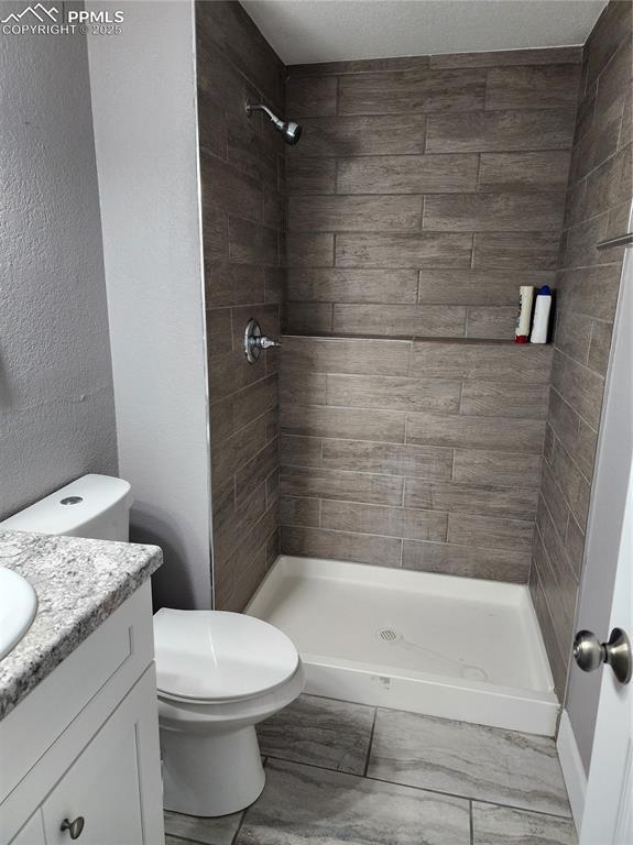 5427 Alteza Dr, Colorado Springs, CO 80917 - full bathroom featuring vanity, a stall shower, and toilet