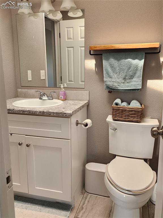 5427 Alteza Dr, Colorado Springs, CO 80917 - half bath with a textured wall, toilet, and vanity