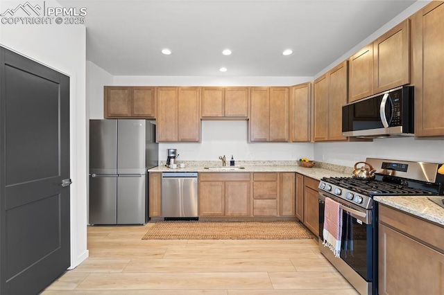 3565 Rosette Grv, Colorado Springs, CO 80910 - kitchen featuring stainless steel appliances, a sink, recessed lighting, light wood-style floors, and light stone counters