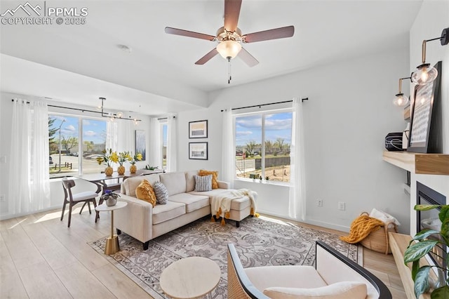 3565 Rosette Grv, Colorado Springs, CO 80910 - living area featuring light wood-style floors, a ceiling fan, a large fireplace, a chandelier, and baseboards