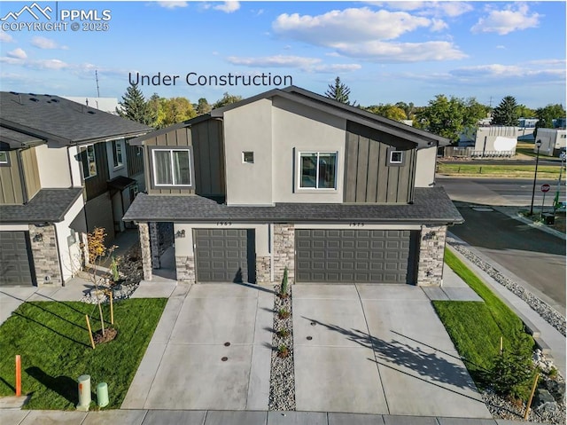 3575 Rosette Grv, Colorado Springs, CO 80910 - view of front facade featuring board and batten siding, a garage, concrete driveway, and stone siding