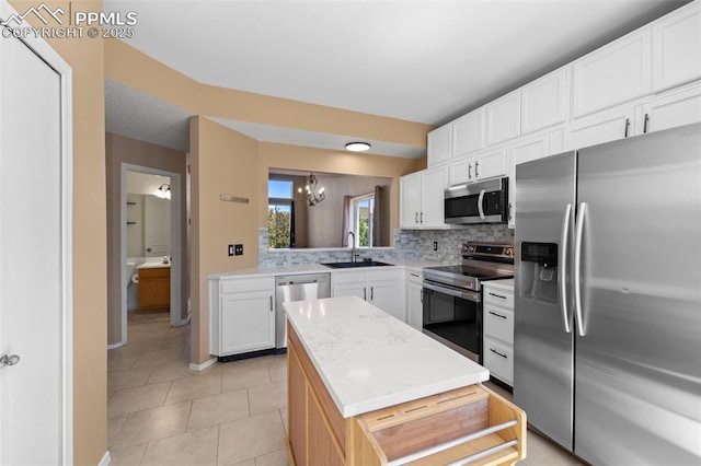 4280 Solarglen Dr, Colorado Springs, CO 80916 - kitchen with stainless steel appliances, a sink, a kitchen island, decorative backsplash, and light countertops