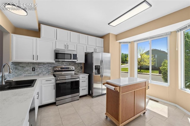 4280 Solarglen Dr, Colorado Springs, CO 80916 - kitchen with stainless steel appliances, a sink, decorative backsplash, white cabinetry, and light tile patterned floors
