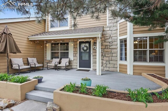 4765 Signal Rock Rd, Colorado Springs, CO 80922 - rear view of property featuring stone siding, covered porch, an outdoor hangout area, and a shingled roof