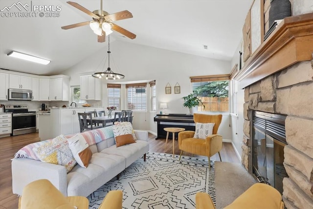 4765 Signal Rock Rd, Colorado Springs, CO 80922 - living area featuring a ceiling fan, a stone fireplace, wood finished floors, baseboards, and high vaulted ceiling