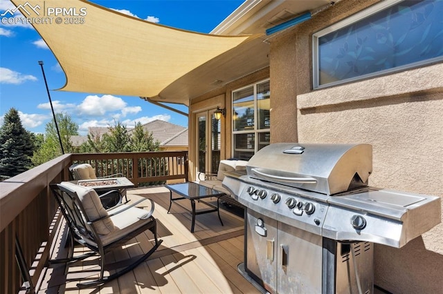 wooden deck featuring area for grilling, french doors, and a fire pit