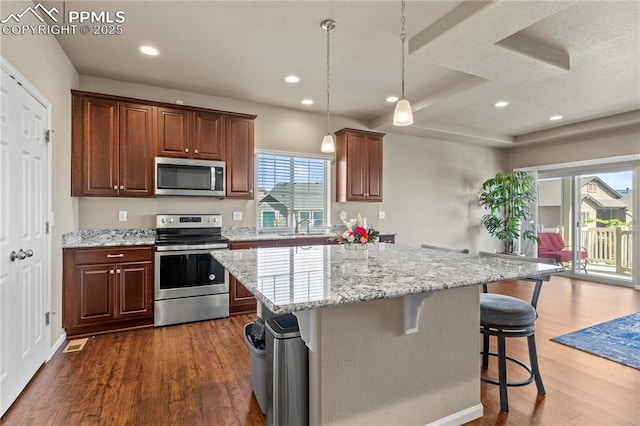6646 Backcountry Loop, Colorado Springs, CO 80927 - kitchen featuring stainless steel appliances, a breakfast bar area, dark wood-style flooring, a center island, and light stone counters